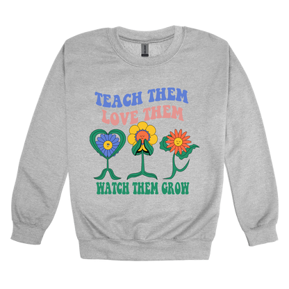 Teach Them Love Them teacher design on Sport Gray adult Crewneck, front view.