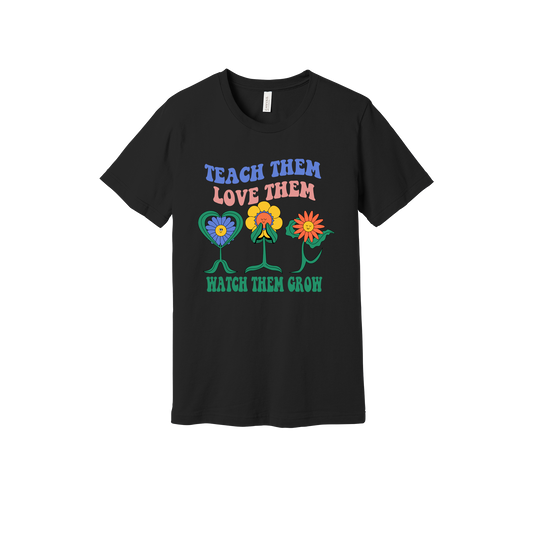 Teach Them Love Them teacher design on Black adult T-Shirt, front view.